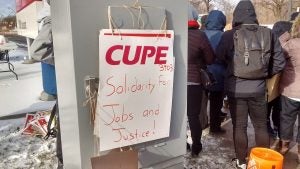 A sign on a picket line reads "Solidarity for Jobs and Justice".